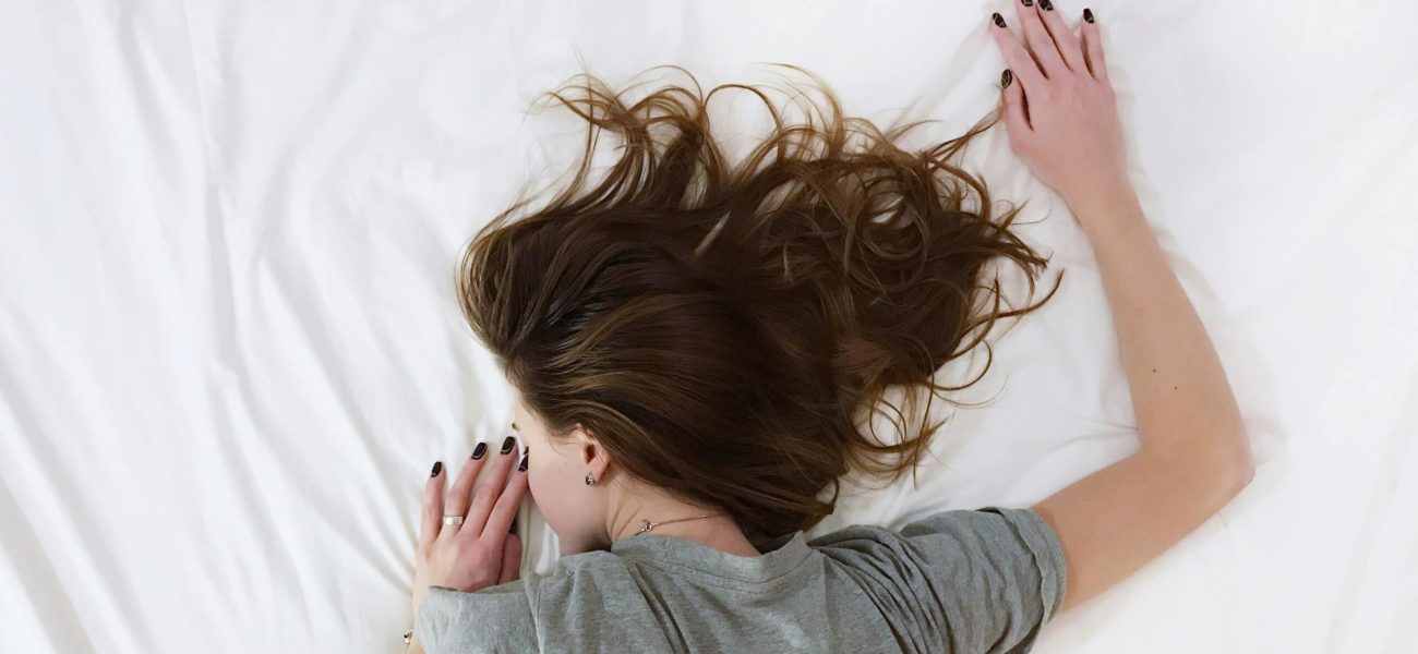 A woman suffering from chronic pain lying face-down on a bed