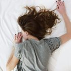 A woman suffering from chronic pain lying face-down on a bed