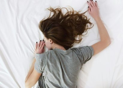 A woman suffering from chronic pain lying face-down on a bed
