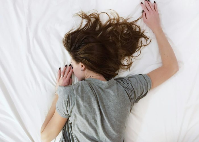 A woman suffering from chronic pain lying face-down on a bed
