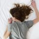 A woman suffering from chronic pain lying face-down on a bed