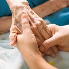 Two hands holding an elderly person's hand