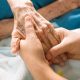 Two hands holding an elderly person's hand