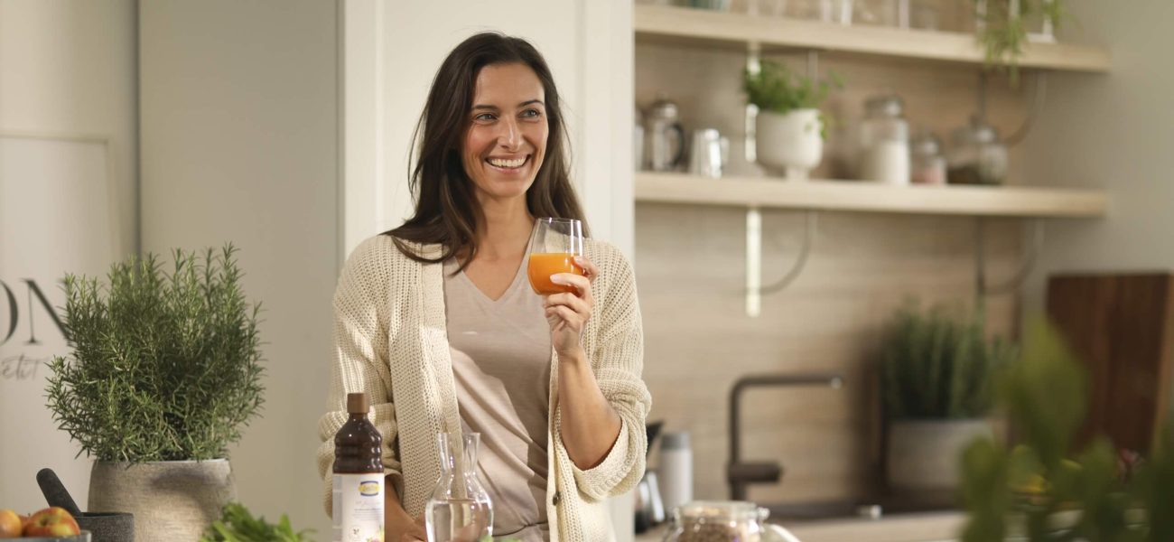 A woman standing in a kitchen holding a glass