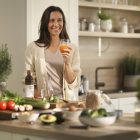 A woman standing in a kitchen holding a glass