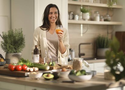 A woman standing in a kitchen holding a glass