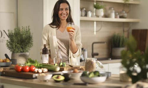 A woman standing in a kitchen holding a glass