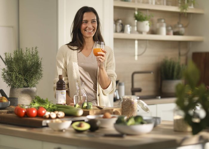 A woman standing in a kitchen holding a glass
