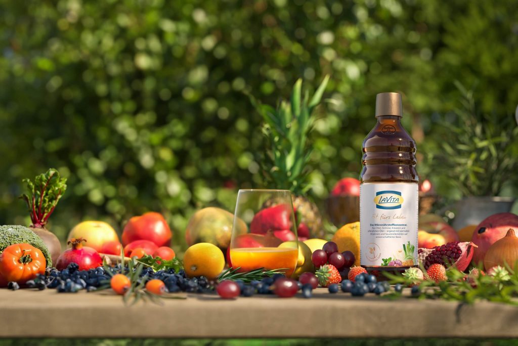 A bottle of LaVita next to a glass and a selection of fruit