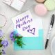 A handwritten Mother's Day card on a table next to a pen and a cup of coffee