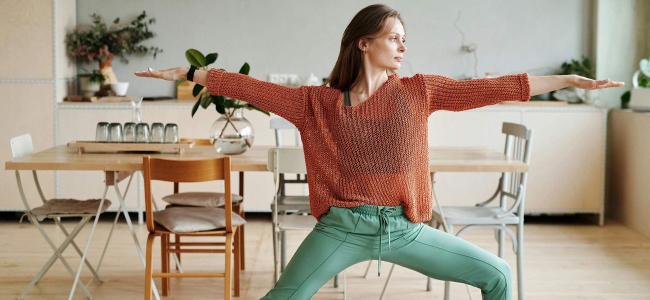 A woman practising a yoga warrior pose at home