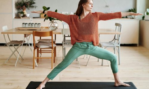 A woman practising a yoga warrior pose at home
