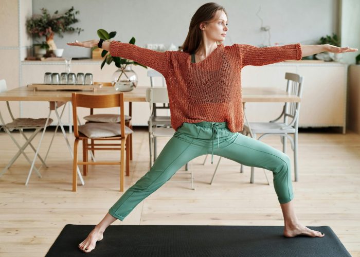 A woman practising a yoga warrior pose at home