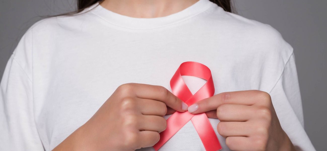 A woman pinning a World Breast Cancer Day ribbon to her white t-shirt