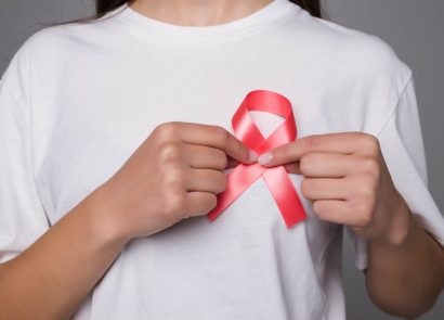 A woman pinning a World Breast Cancer Day ribbon to her white t-shirt
