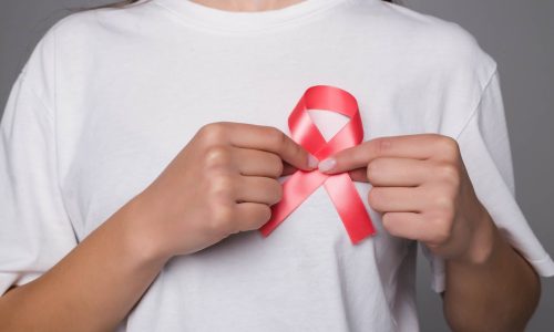 A woman pinning a World Breast Cancer Day ribbon to her white t-shirt