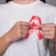 A woman pinning a World Breast Cancer Day ribbon to her white t-shirt