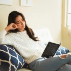 A woman reading a book on a sofa at home
