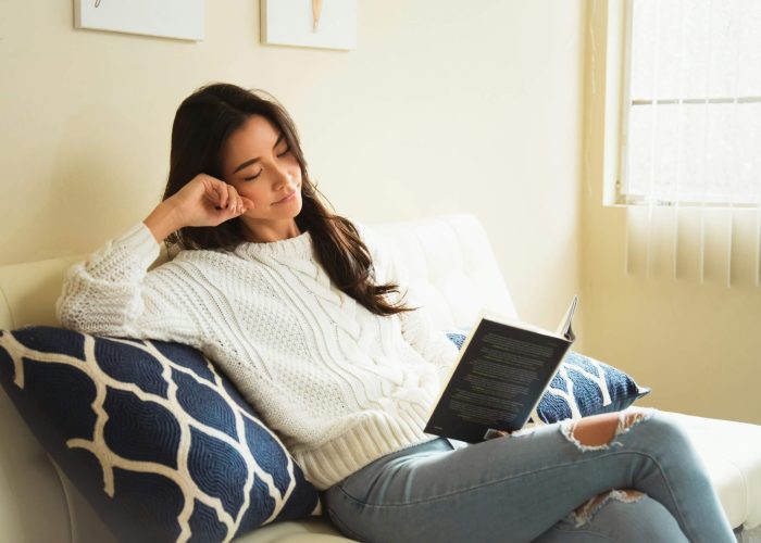 A woman reading a book on a sofa at home
