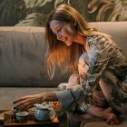 A woman sitting on a sofa in her pyjamas preparing a cup of tea