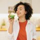A woman in a kitchen drinking a green smoothie