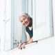 An elderly woman leaning out of an upstairs window of her home