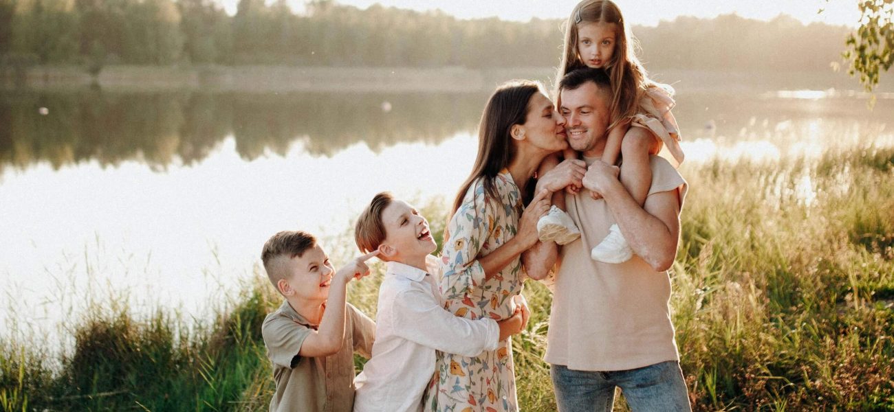 A husband and wife with their children standing beside a river in the summer