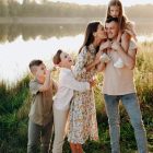 A husband and wife with their children standing beside a river in the summer