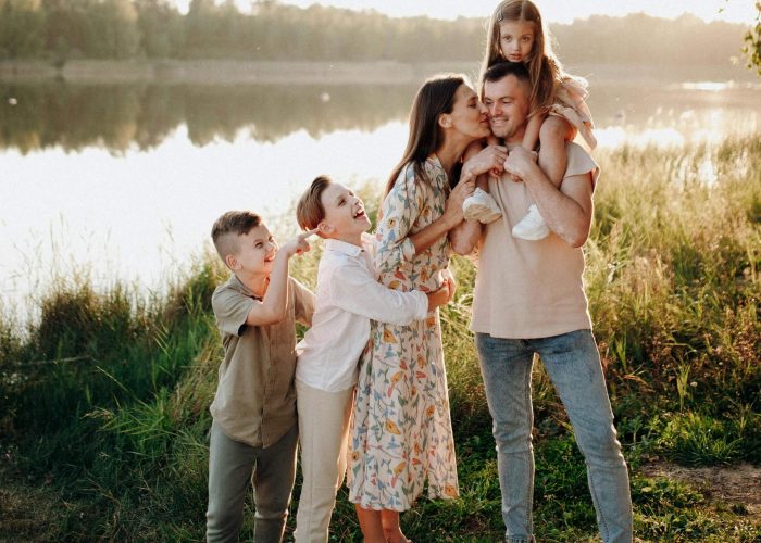 A husband and wife with their children standing beside a river in the summer