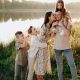 A husband and wife with their children standing beside a river in the summer