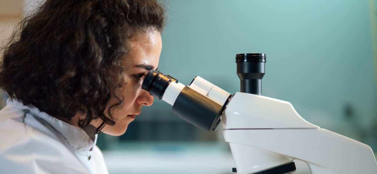 A female scientist looking through a microscope in a lab