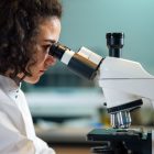 A female scientist looking through a microscope in a lab