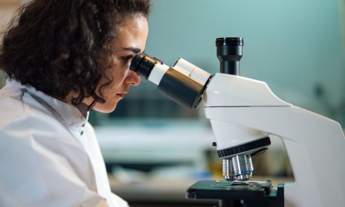 A female scientist looking through a microscope in a lab