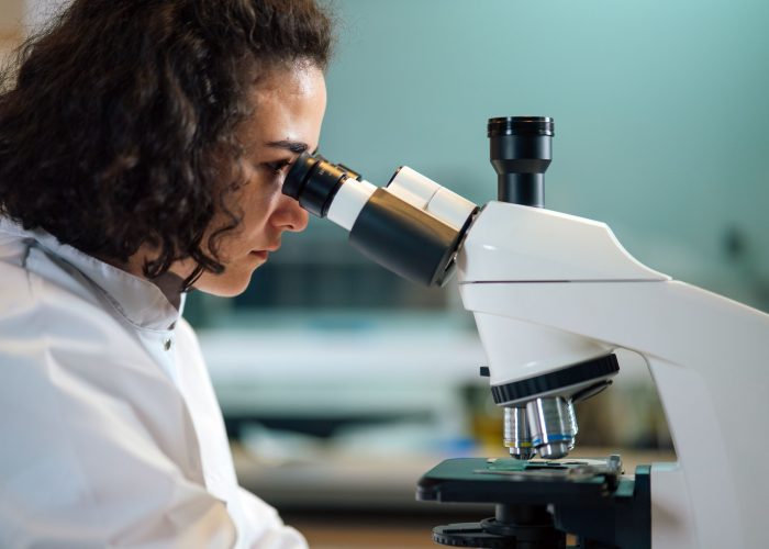 A female scientist looking through a microscope in a lab
