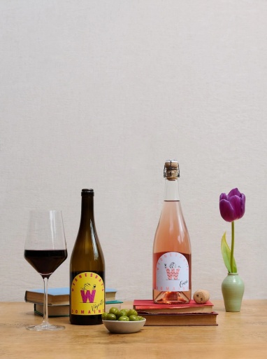 Two bottles of Wednesday’s Domaine wines on a table with a wine glass