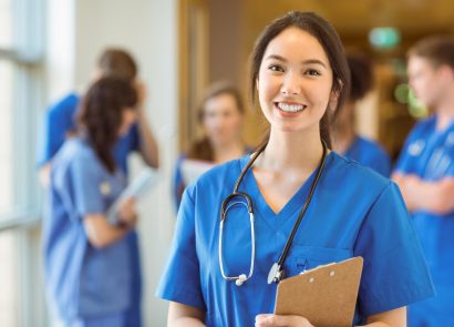 A female doctor with a stethoscope looking at the camera and smiling