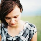A woman with brown hair walking outside, looking down towards the ground