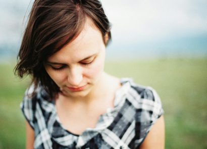 A woman with brown hair walking outside, looking down towards the ground