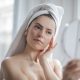 A woman in her bathroom looking into a mirror as part of her skincare routine