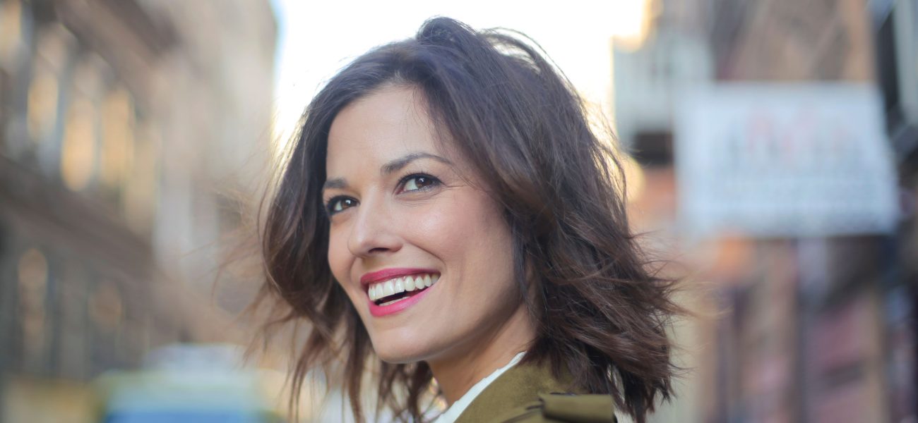 A woman with perfect white teeth smiling on a city street