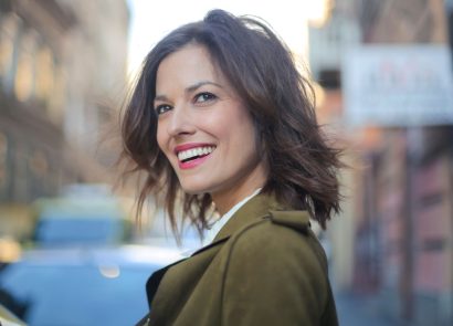 A woman with perfect white teeth smiling on a city street