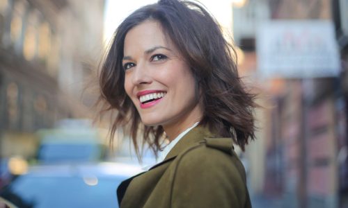 A woman with perfect white teeth smiling on a city street