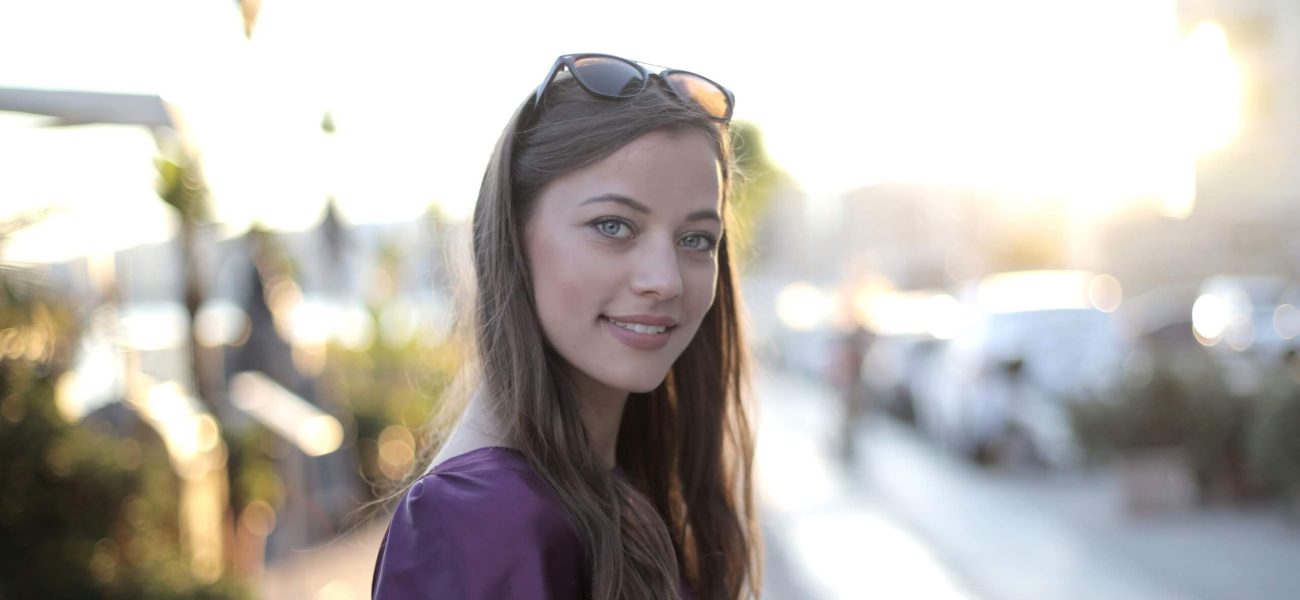 A smiling woman holding a shopping bag on a city street