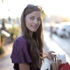 A smiling woman holding a shopping bag on a city street