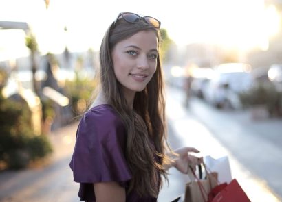 A smiling woman holding a shopping bag on a city street