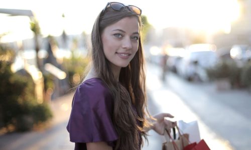 A smiling woman holding a shopping bag on a city street