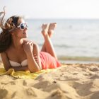 A woman in sunglasses lying on the beach on a summer's day