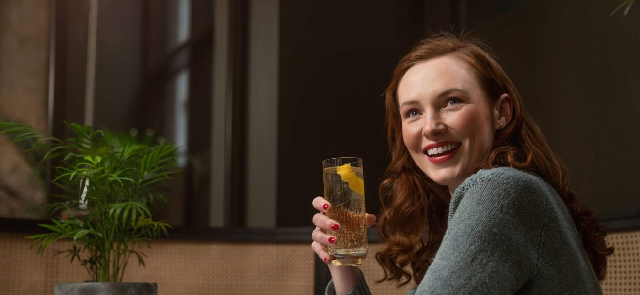 A smiling woman sitting enjoying a cocktail