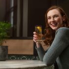 A smiling woman sitting enjoying a cocktail