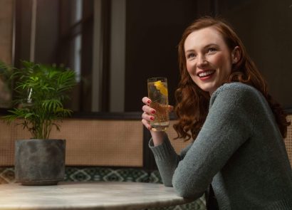 A smiling woman sitting enjoying a cocktail